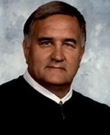 Portrait of a male judge in black robe.